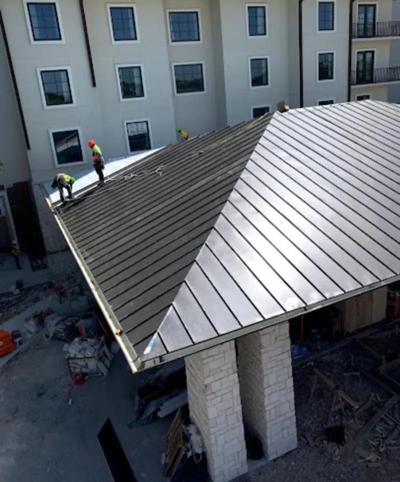 Crew installing standing seam metal roof panels on a commercial project in Montgomery